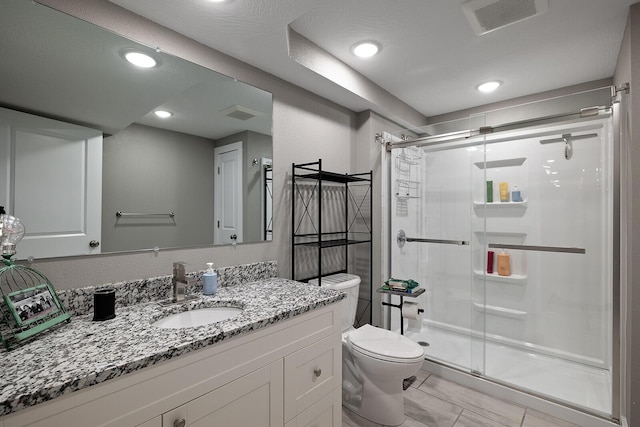 bathroom with vanity, a shower with shower door, and toilet