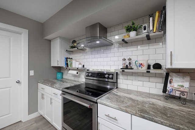 kitchen featuring electric stove, white cabinets, wall chimney exhaust hood, and decorative backsplash