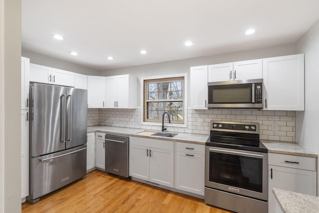 kitchen with white cabinets, light hardwood / wood-style floors, sink, and appliances with stainless steel finishes