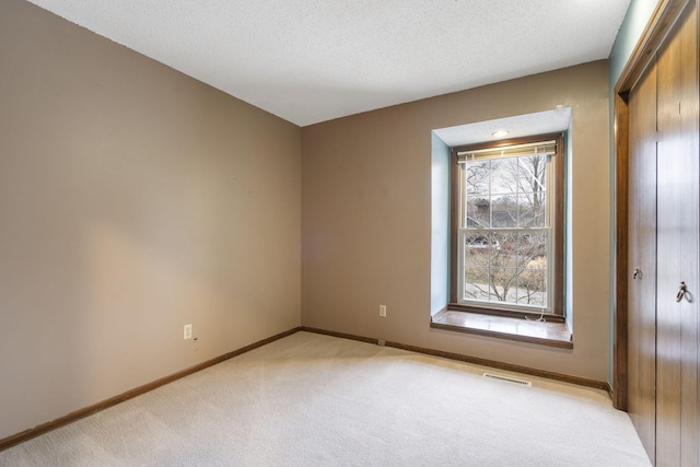 spare room featuring a textured ceiling and light carpet