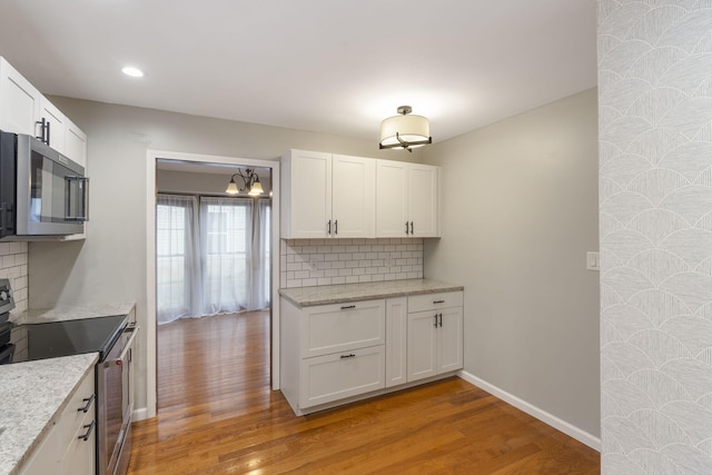 kitchen with tasteful backsplash, white cabinetry, light hardwood / wood-style flooring, and appliances with stainless steel finishes