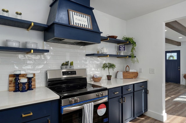 kitchen with hardwood / wood-style floors, decorative backsplash, blue cabinetry, range hood, and stainless steel range oven