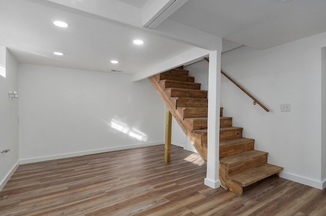 staircase with beam ceiling and hardwood / wood-style flooring