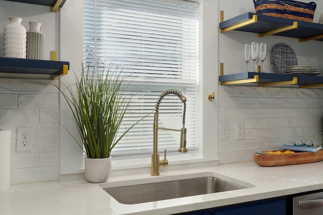 interior details with decorative backsplash, sink, and light stone counters