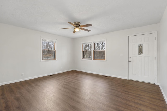 spare room featuring dark hardwood / wood-style floors, ceiling fan, and a textured ceiling