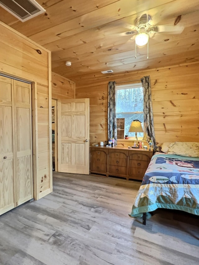 bedroom with ceiling fan, wood walls, light wood-type flooring, and wooden ceiling