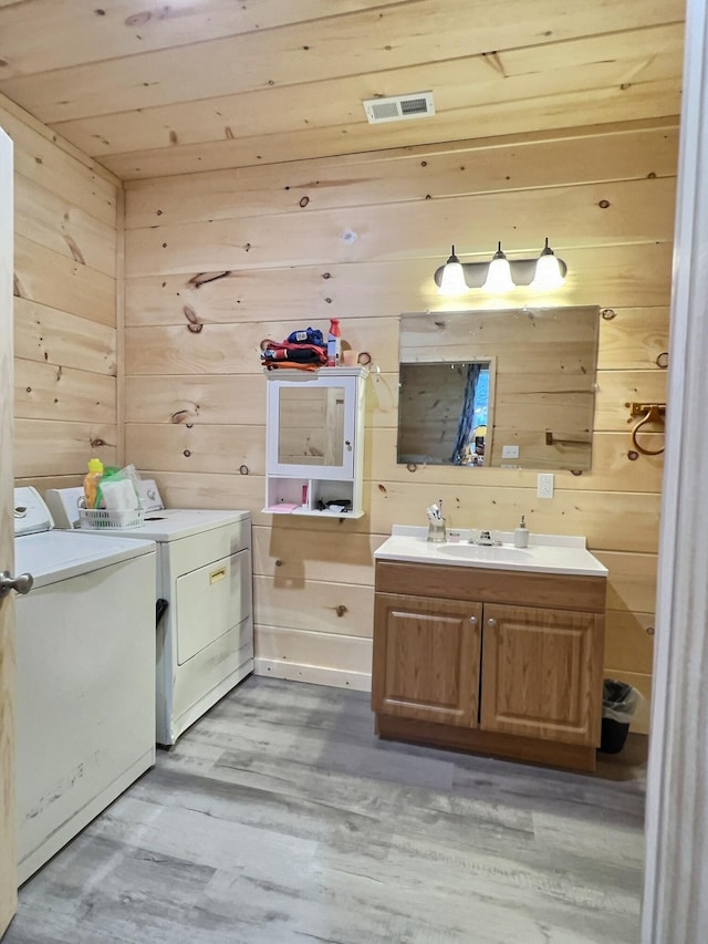 bathroom featuring vanity, wooden walls, and washing machine and clothes dryer