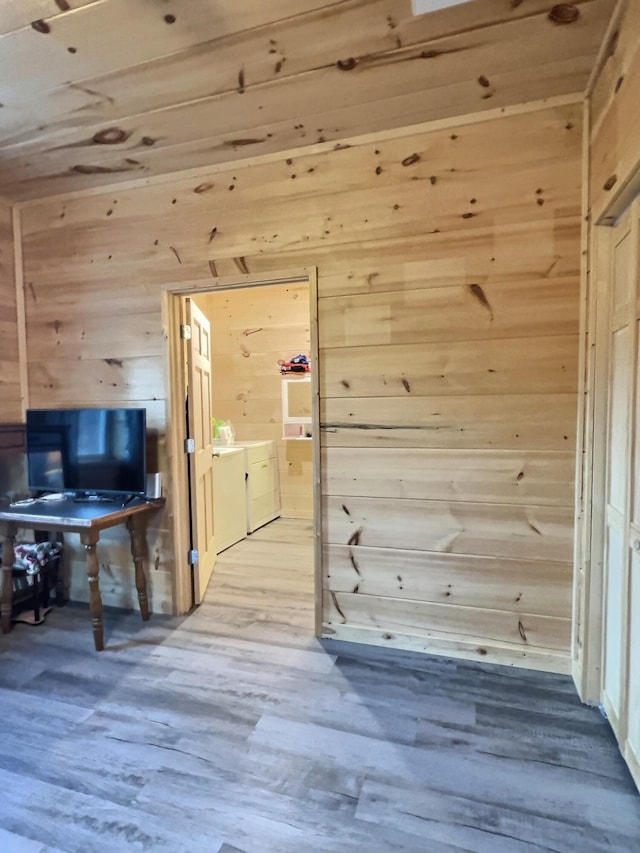 bonus room with washing machine and dryer, wooden walls, and hardwood / wood-style flooring