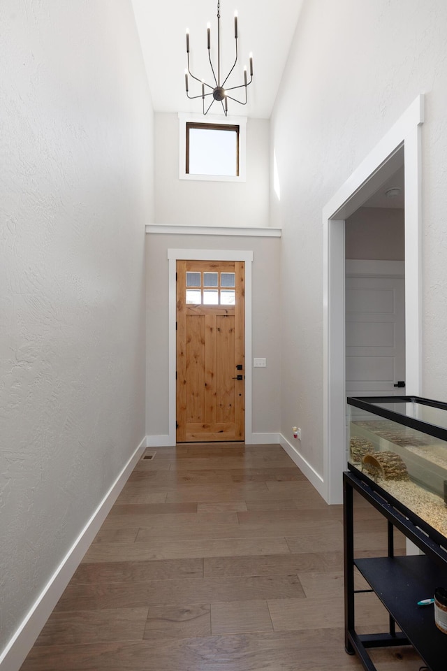 entrance foyer featuring light wood-type flooring, a healthy amount of sunlight, and a notable chandelier