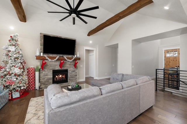 living room featuring dark hardwood / wood-style flooring, lofted ceiling with beams, a stone fireplace, and ceiling fan