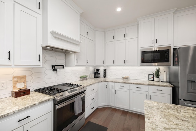 kitchen with light stone countertops, dark hardwood / wood-style floors, decorative backsplash, white cabinets, and appliances with stainless steel finishes