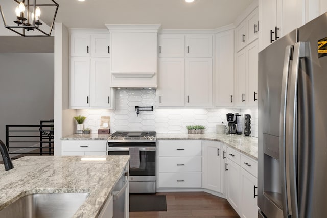 kitchen featuring hanging light fixtures, white cabinets, stainless steel appliances, and sink