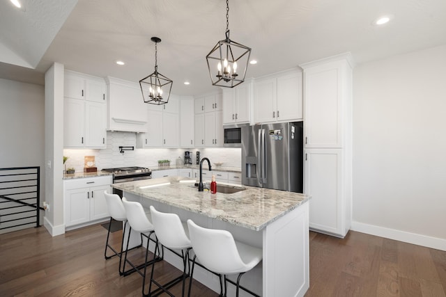 kitchen featuring light stone countertops, appliances with stainless steel finishes, sink, white cabinetry, and an island with sink