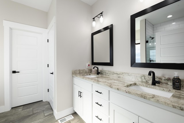 bathroom with a tile shower and vanity