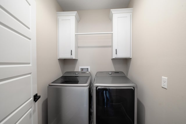 laundry area featuring separate washer and dryer and cabinets