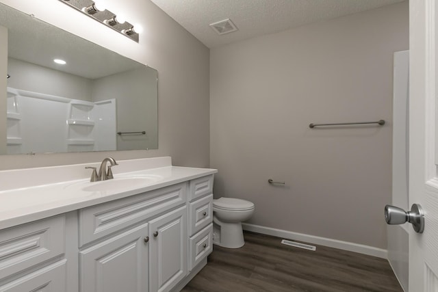 bathroom featuring walk in shower, vanity, a textured ceiling, hardwood / wood-style floors, and toilet