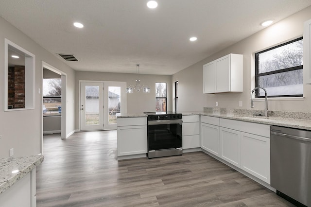 kitchen featuring white cabinets, appliances with stainless steel finishes, a notable chandelier, and sink