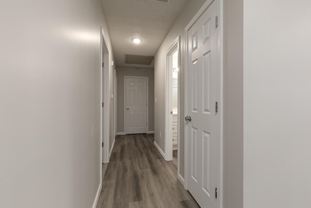 hall with hardwood / wood-style floors and a textured ceiling