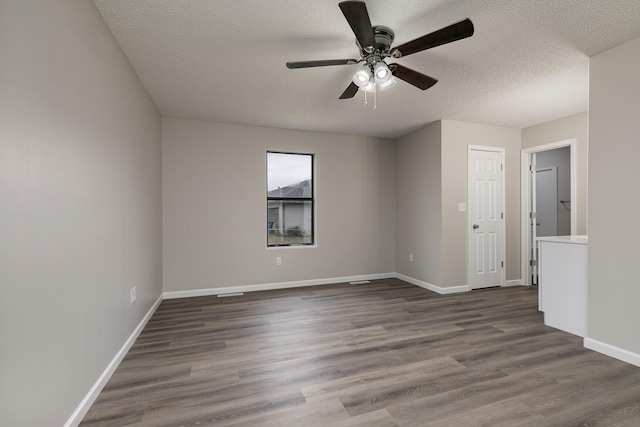 unfurnished room with ceiling fan, a textured ceiling, and dark wood-type flooring