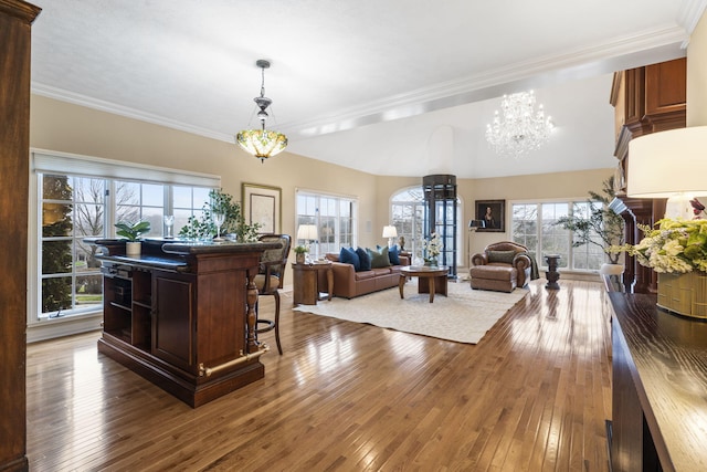 kitchen with hanging light fixtures, hardwood / wood-style flooring, ornamental molding, a kitchen bar, and a chandelier