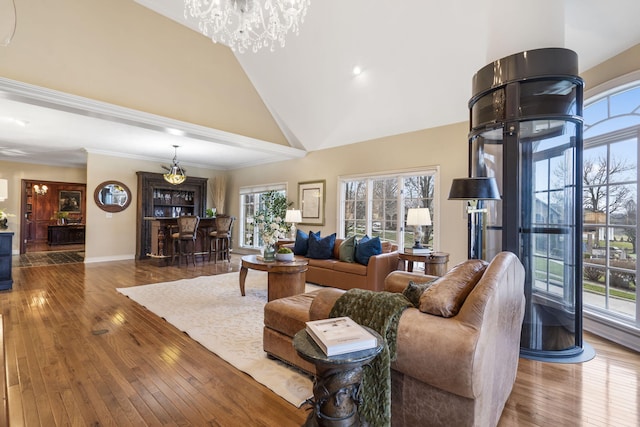 living room with hardwood / wood-style flooring, ornamental molding, high vaulted ceiling, and a chandelier