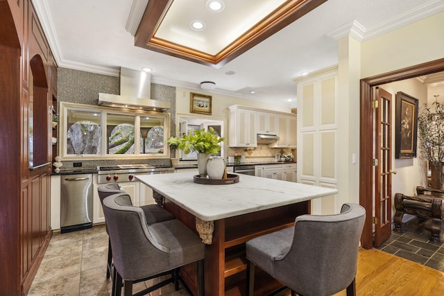 dining area featuring ornamental molding, a tray ceiling, and light hardwood / wood-style flooring