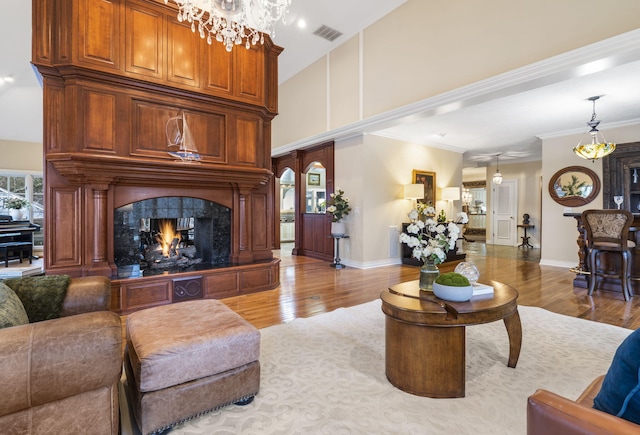 living room with light wood-type flooring, crown molding, a high ceiling, and an inviting chandelier