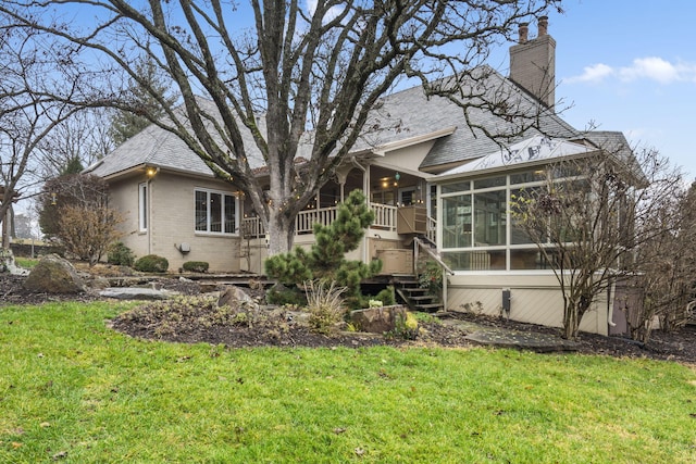 rear view of property featuring a sunroom and a yard