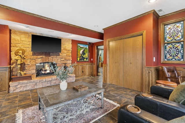 living room with a stone fireplace and crown molding