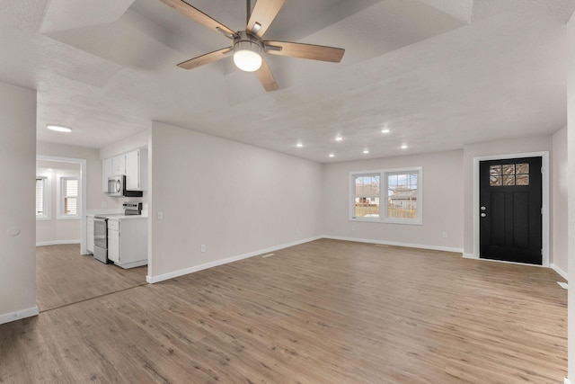 unfurnished living room with ceiling fan, light hardwood / wood-style floors, and a healthy amount of sunlight