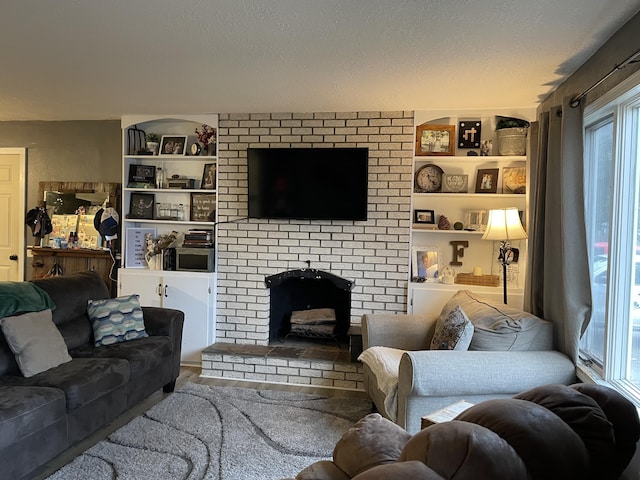 living room featuring built in shelves, a textured ceiling, and a brick fireplace