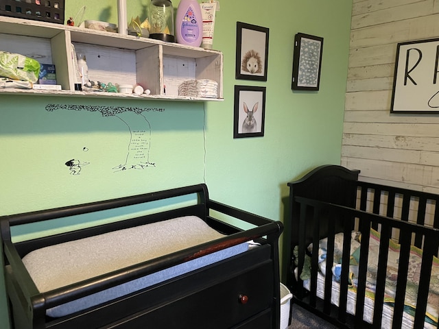 bedroom featuring a nursery area and wood walls