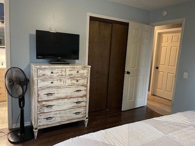 bedroom with dark hardwood / wood-style floors and a closet