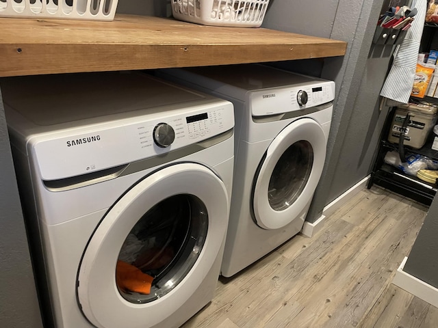 clothes washing area featuring washer and dryer and light wood-type flooring