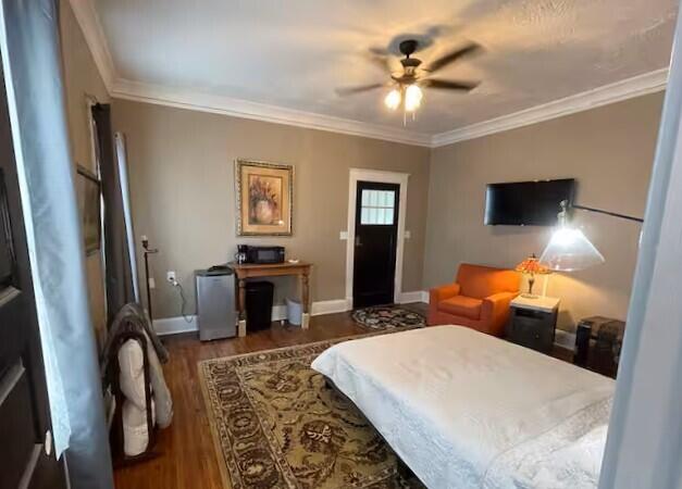 bedroom featuring ceiling fan, crown molding, and dark hardwood / wood-style floors