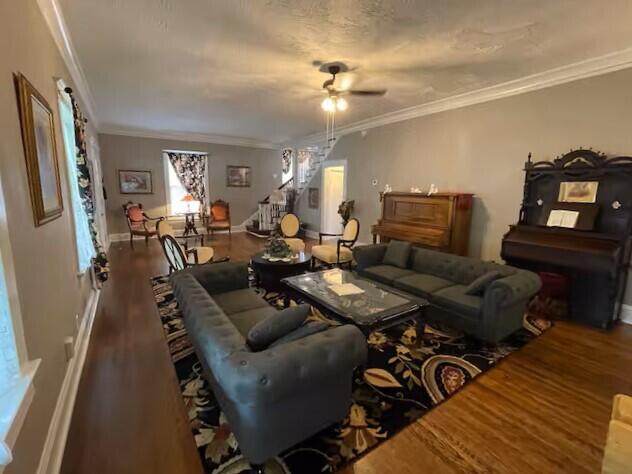 living room with crown molding, ceiling fan, and wood-type flooring