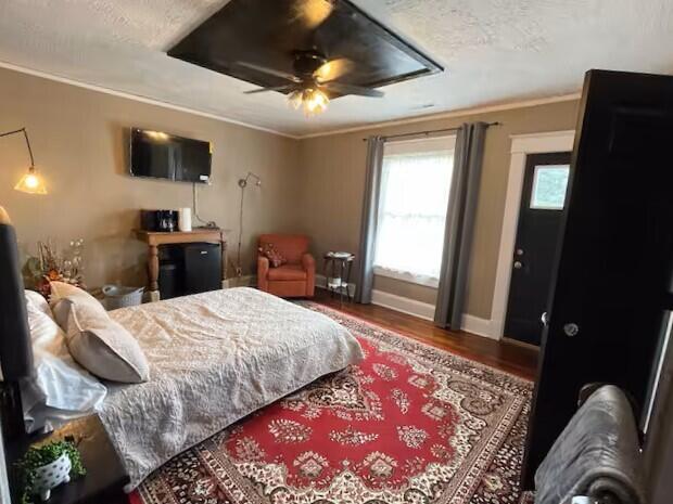 bedroom featuring a textured ceiling, hardwood / wood-style flooring, ceiling fan, and ornamental molding