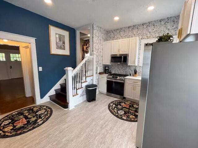 kitchen with white cabinetry, light hardwood / wood-style flooring, appliances with stainless steel finishes, and tasteful backsplash