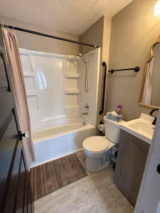 full bathroom with toilet, vanity, a textured ceiling, and washtub / shower combination