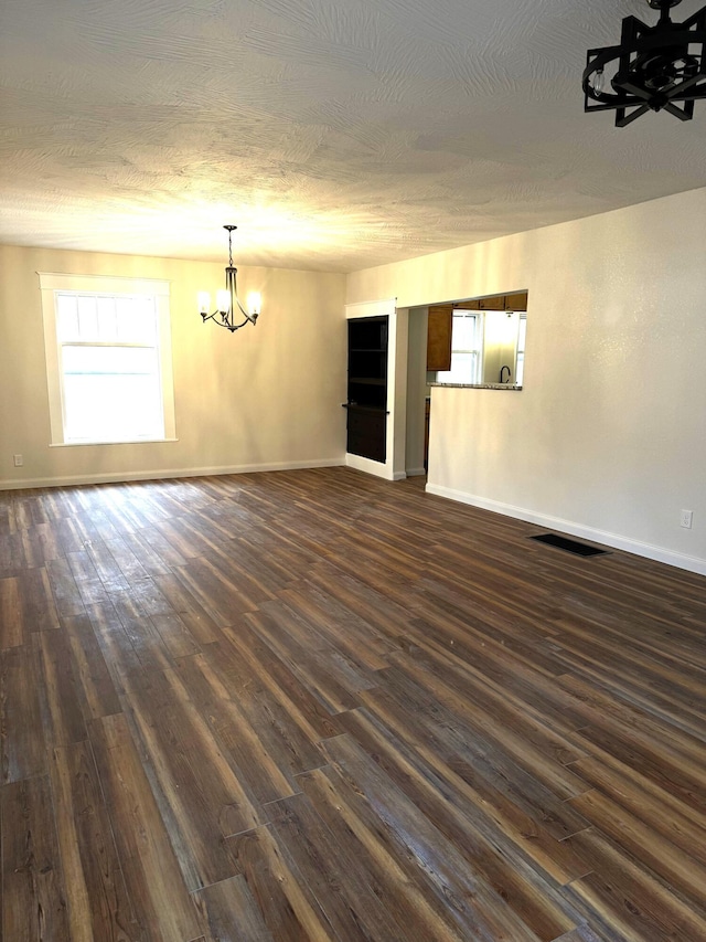 unfurnished room with dark hardwood / wood-style flooring, a chandelier, and a textured ceiling