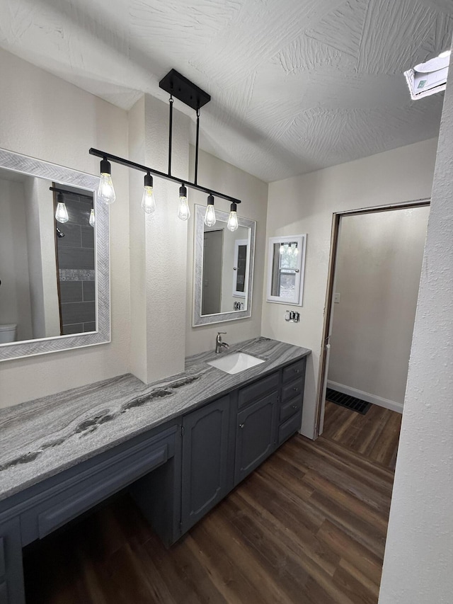 bathroom with hardwood / wood-style floors, vanity, toilet, and a skylight