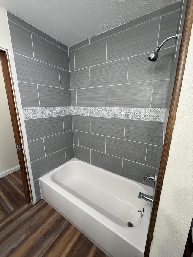 bathroom with hardwood / wood-style floors and washtub / shower combination