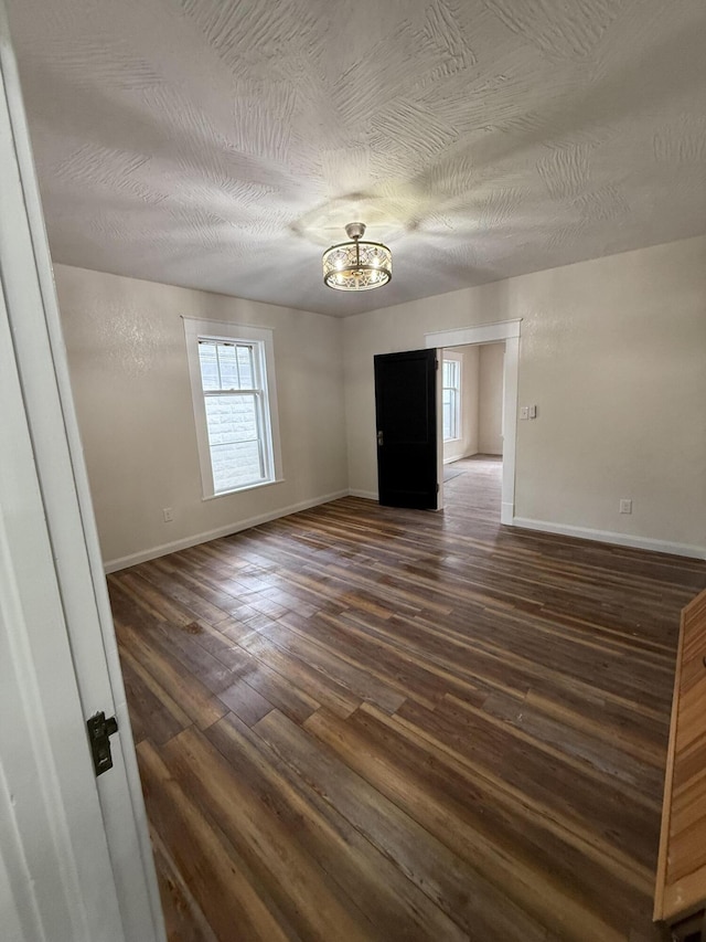 empty room with dark hardwood / wood-style floors and a textured ceiling