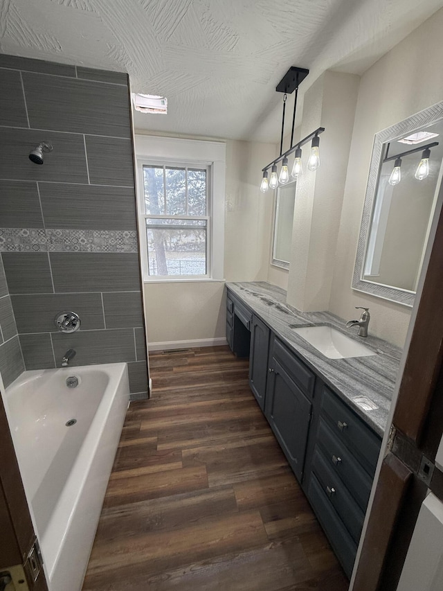 bathroom with hardwood / wood-style floors, vanity, a textured ceiling, and tiled shower / bath combo