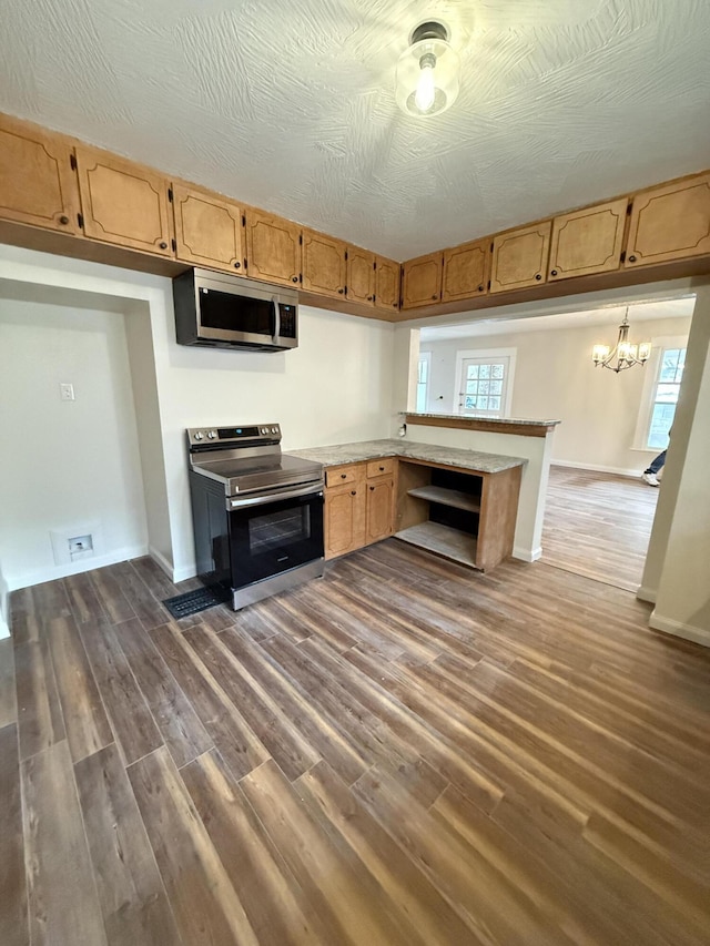 kitchen with hanging light fixtures, dark hardwood / wood-style floors, appliances with stainless steel finishes, kitchen peninsula, and a chandelier