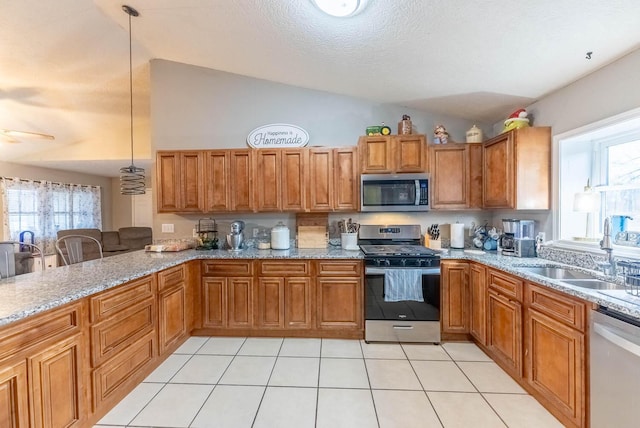 kitchen featuring pendant lighting, sink, appliances with stainless steel finishes, and vaulted ceiling