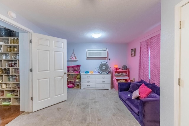 sitting room featuring a wall mounted AC, light colored carpet, and a textured ceiling