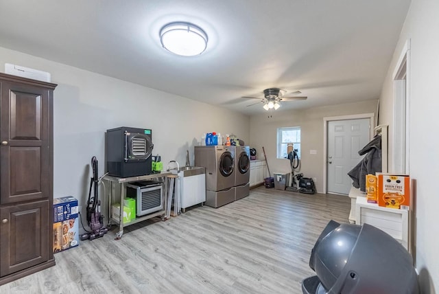 clothes washing area featuring washing machine and dryer, light hardwood / wood-style flooring, and ceiling fan