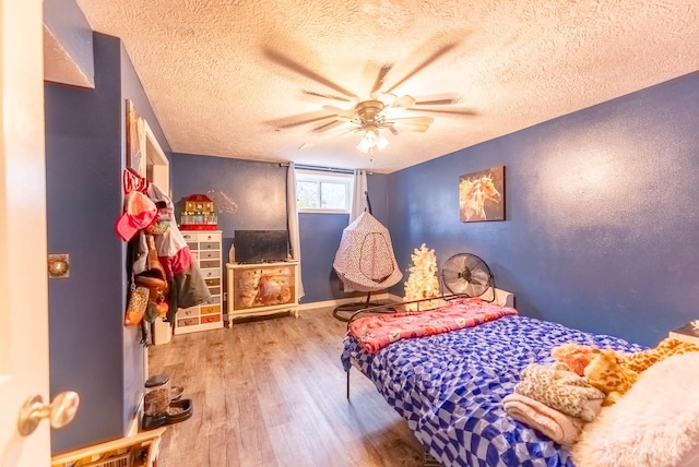 bedroom with ceiling fan, wood-type flooring, and a textured ceiling