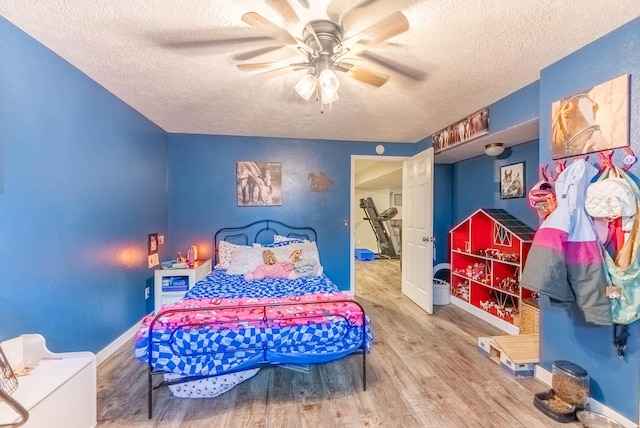 bedroom featuring ceiling fan, wood-type flooring, and a textured ceiling